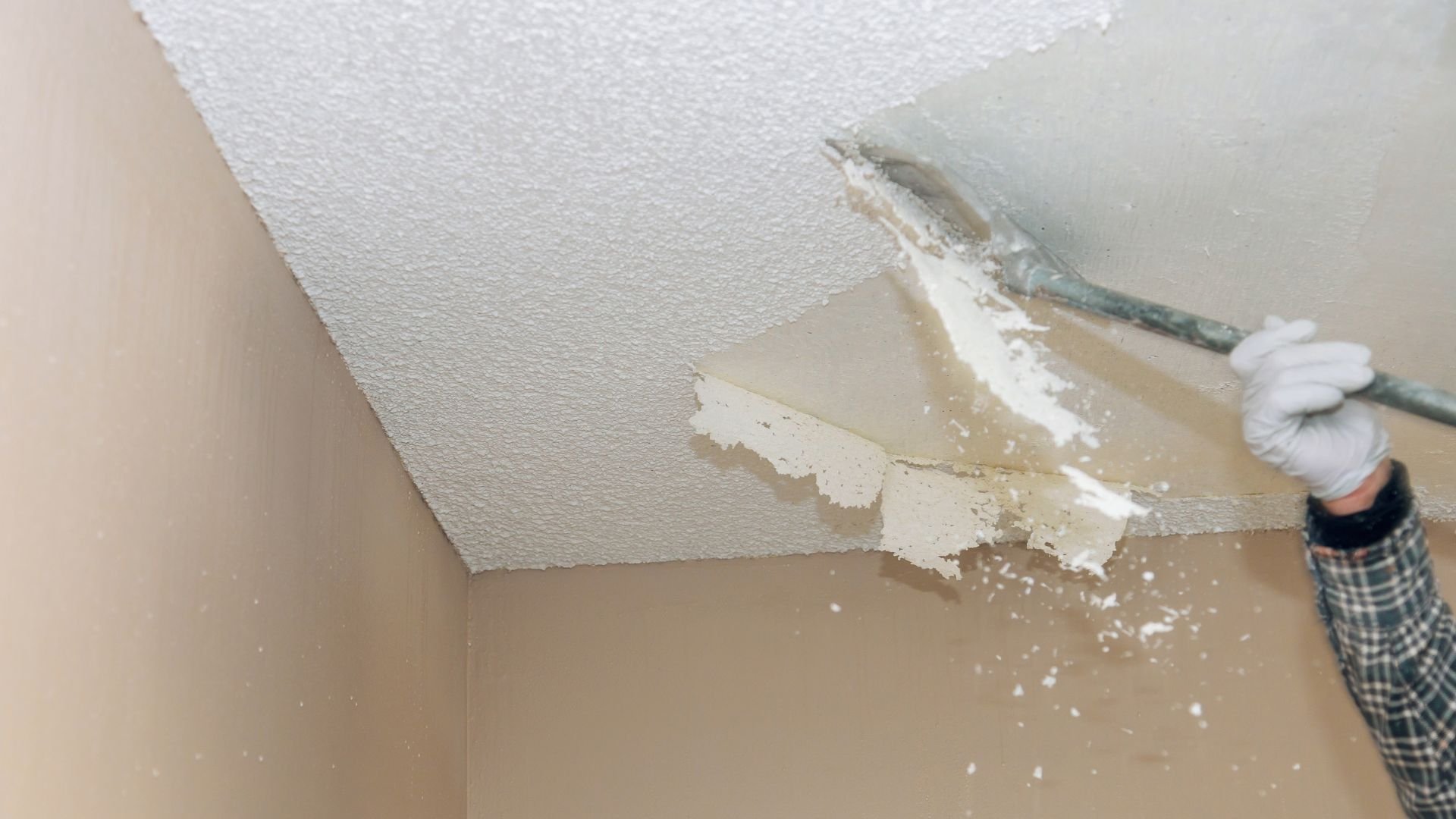 Scraping textured ceiling with putty knife during home renovation