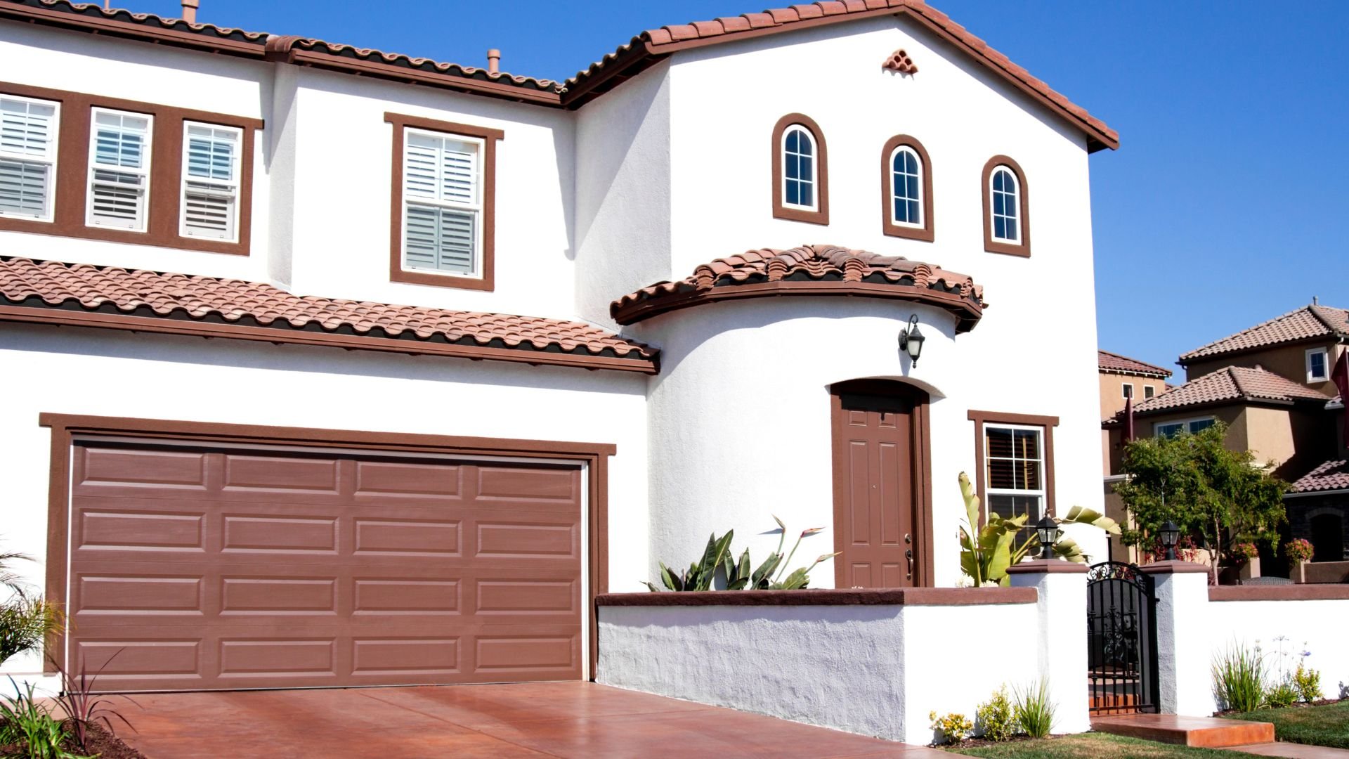 White and brown Spanish-style two-story house with tiled roof and garage
