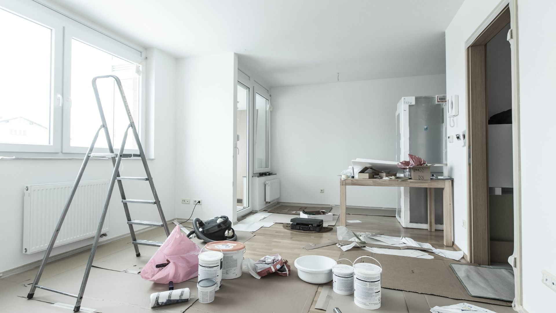 Room in progress of renovation with ladder, paint cans, and construction materials