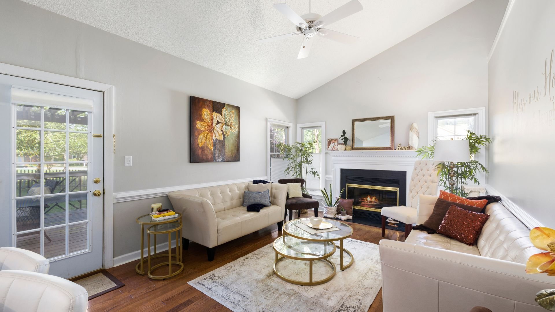 Cozy living room with fireplace, white sofas, golden accents, and floral artwork